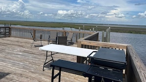 Una terraza de madera con una mesa y sillas, con vista a un paisaje pantanoso.