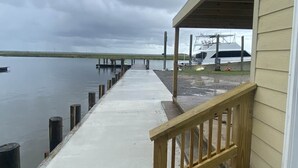 A pier extending into calm water with a covered walkway and a boat docked nearby.