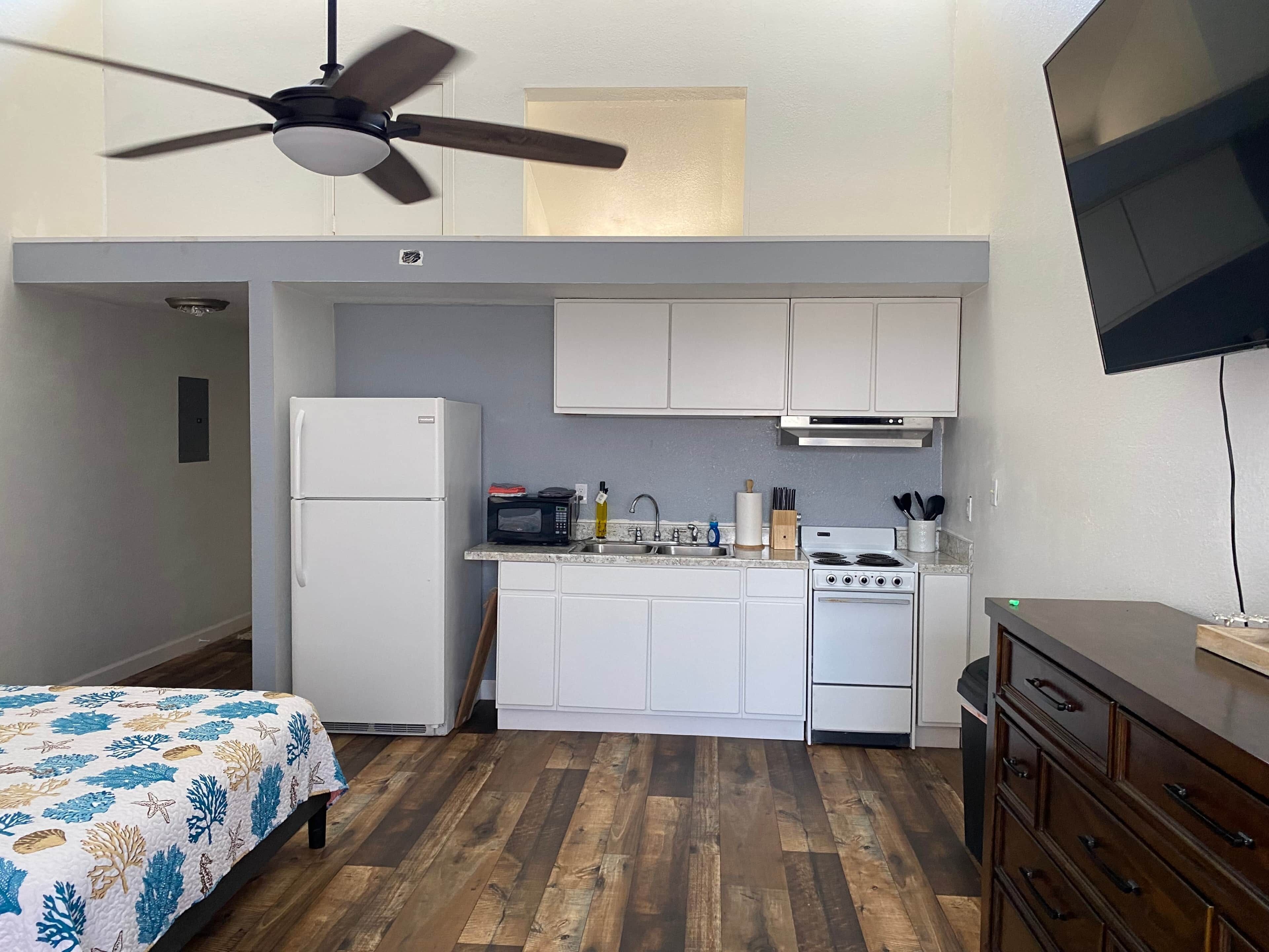 Una cocina compacta con refrigerador, microondas, estufa y lavamanos.