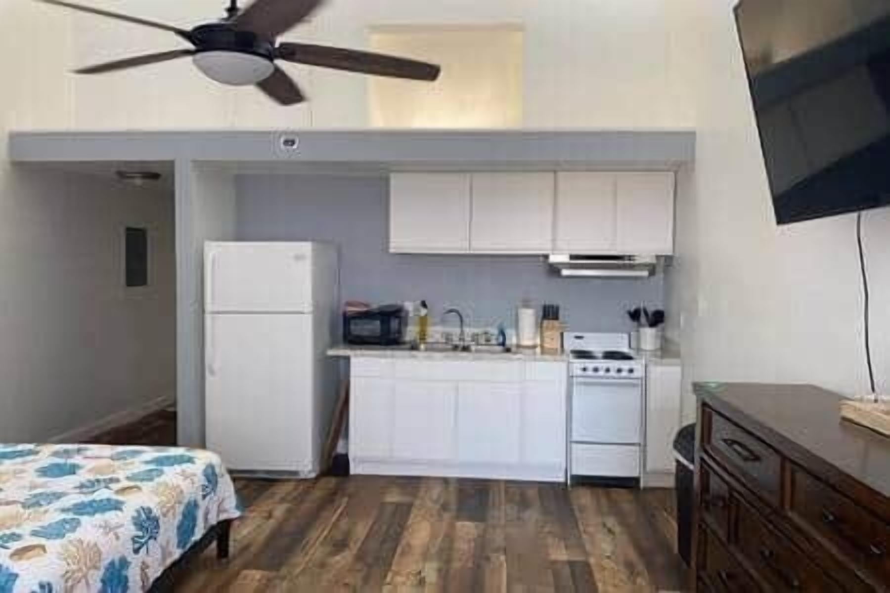A compact kitchen with white cabinets, a refrigerator, a stove, and a microwave.