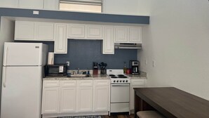 A compact kitchen with white cabinetry, a built-in microwave, a stove, and a ceiling fan. - Legend Oaks room 4 over the water (Gautier)