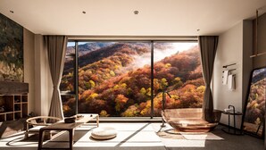 Un intérieur moderne doté d’une grande fenêtre donnant sur une colline boisée.