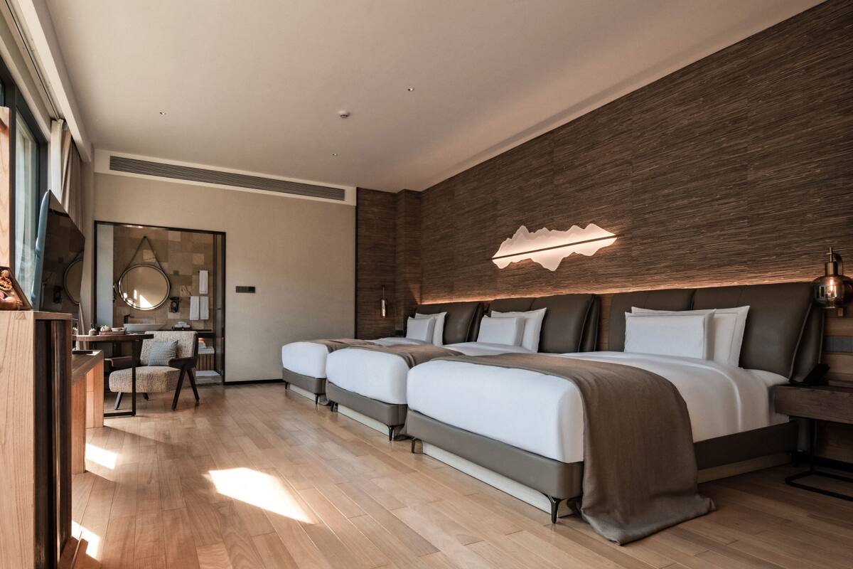 A modern hotel room with a large bed, a desk, and a mirror.