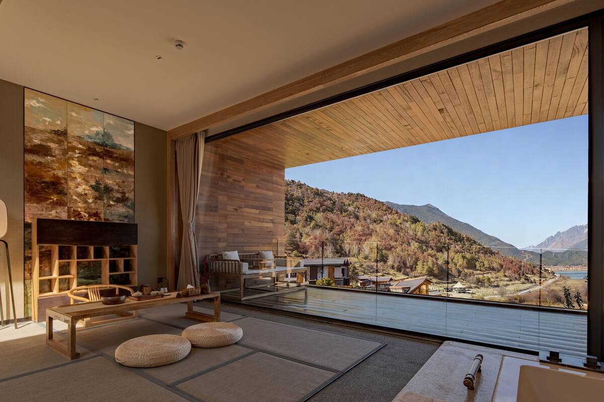 A modern interior with a large window, wooden ceiling, and a view of a mountainous landscape.