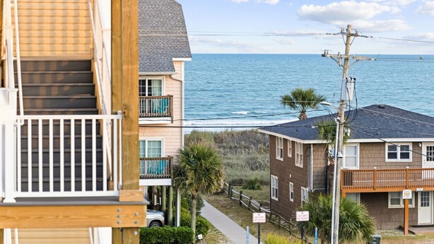A coastal residential area with houses, a wooden staircase, and a view of the ocean. - Tropical Castle | 12BR Retreat w/ Pool | Sleeps 50 (North Myrtle Beach)