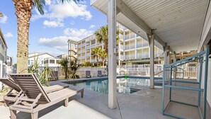 A poolside area with lounge chairs, a pool, and a covered walkway. - Tropical Castle | 12BR Retreat w/ Pool | Sleeps 50 (North Myrtle Beach)