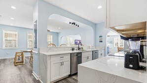 A modern kitchen with white cabinetry, a marble countertop, and stainless steel appliances. - Tropical Castle | 12BR Retreat w/ Pool | Sleeps 50 (North Myrtle Beach)