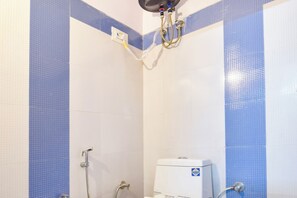 Une douche avec des toilettes blanches et des murs recouverts de carreaux bleus.
