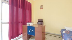A reception desk with a 'Via' sign, a brown leather chair, a framed picture on the wall, and a patterned tablecloth. - Via Kanha Shiva (Ayodhya)