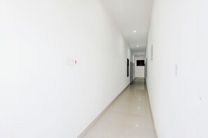 A long, narrow hallway with white walls and a shiny tiled floor. - Via Kanha Shiva (Ayodhya)
