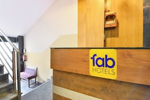 Un mostrador de recepción con un cartel de 'fab hotels', un extintor y una silla.