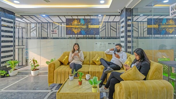 A modern waiting area with a sofa, coffee table, and potted plants.