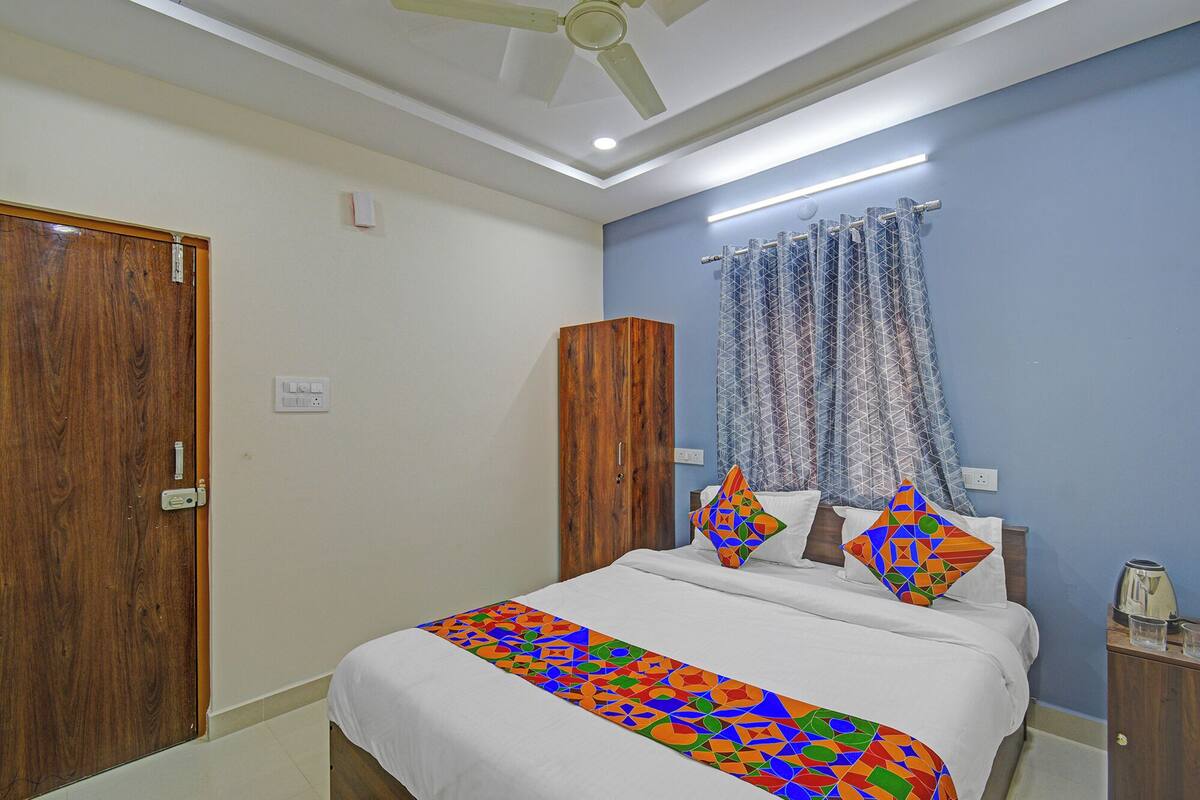 A bedroom with a bed, a wardrobe, a ceiling fan, and a window with curtains.