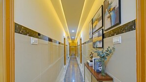 A hotel hallway with a marble floor, wall-mounted artwork, and a console table with decorative items.