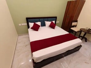 A neatly made bed with a white and red bedspread, a dark headboard, and two red pillows. - FabHotel Rudra Shivalika Jaipur (Jaipur)