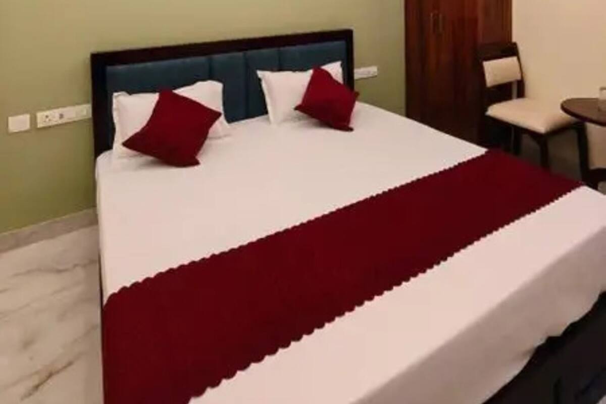 A hotel room with a bed, a ceiling fan, a wardrobe, and a small table.