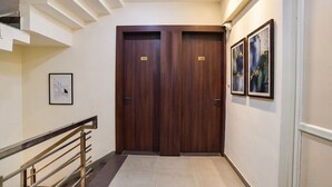 A hallway with two wooden doors marked 101 and 102, a staircase to the left, and framed artwork on the walls. - Fabhotel Nexus (Indore)