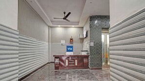 Un área de recepción con mostrador, ventilador de techo y un cartel de 'No Fumar'.