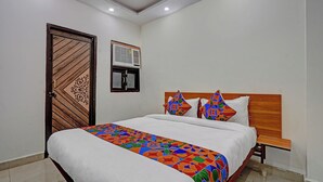 Un dormitorio con cama, puerta de madera, unidad de aire acondicionado y ventana.