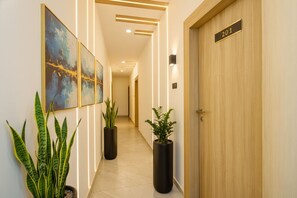 A hallway with a wooden door labeled "201", potted plants, and framed artwork on the walls. - FabHotel Lake View Castle - Bhadrakali Temple, Shyampet (Hanmakonda)