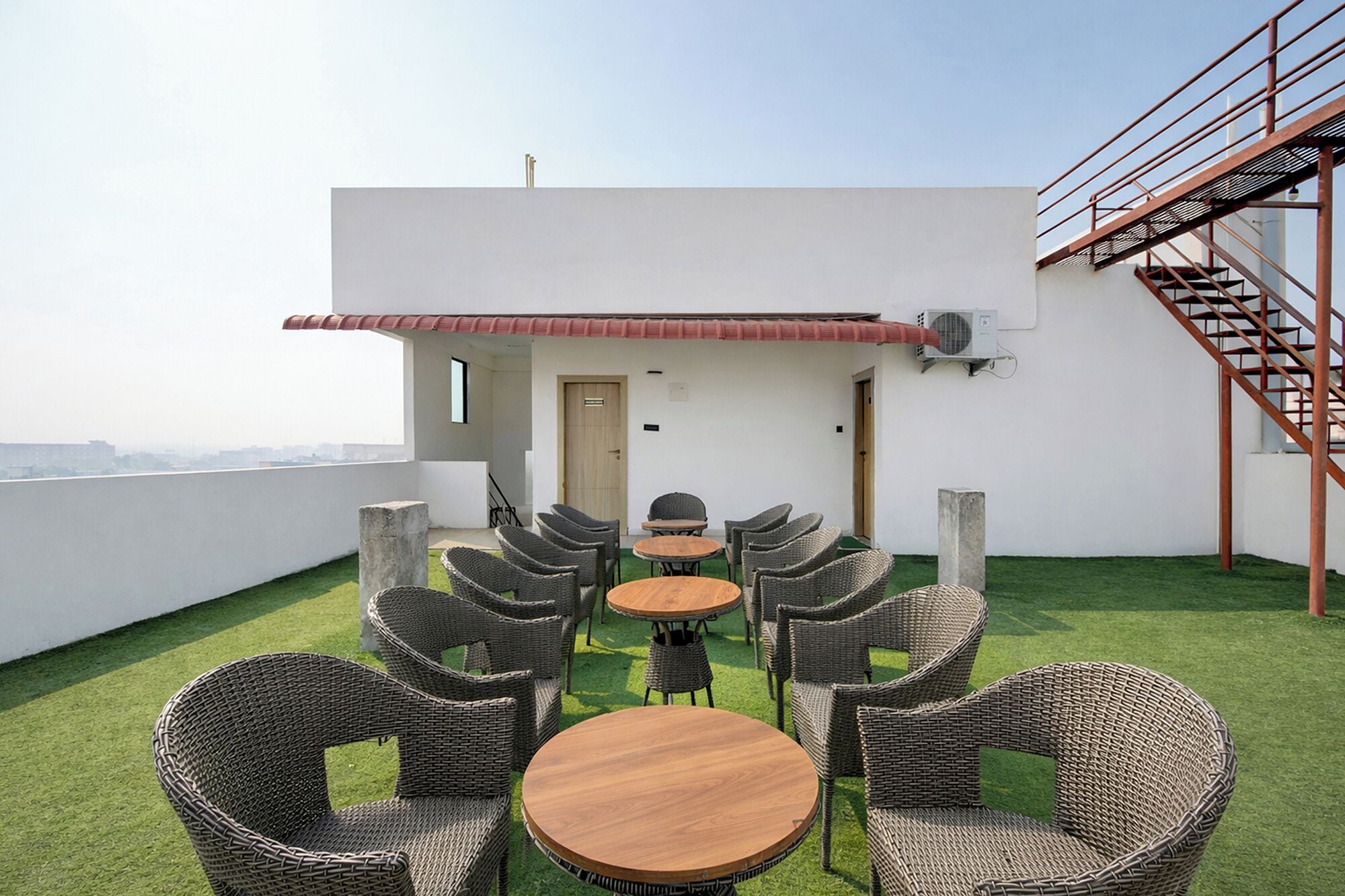A rooftop terrace with wicker furniture, a small table, and a staircase.