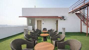 A rooftop terrace with wicker furniture, a small table, and a staircase.