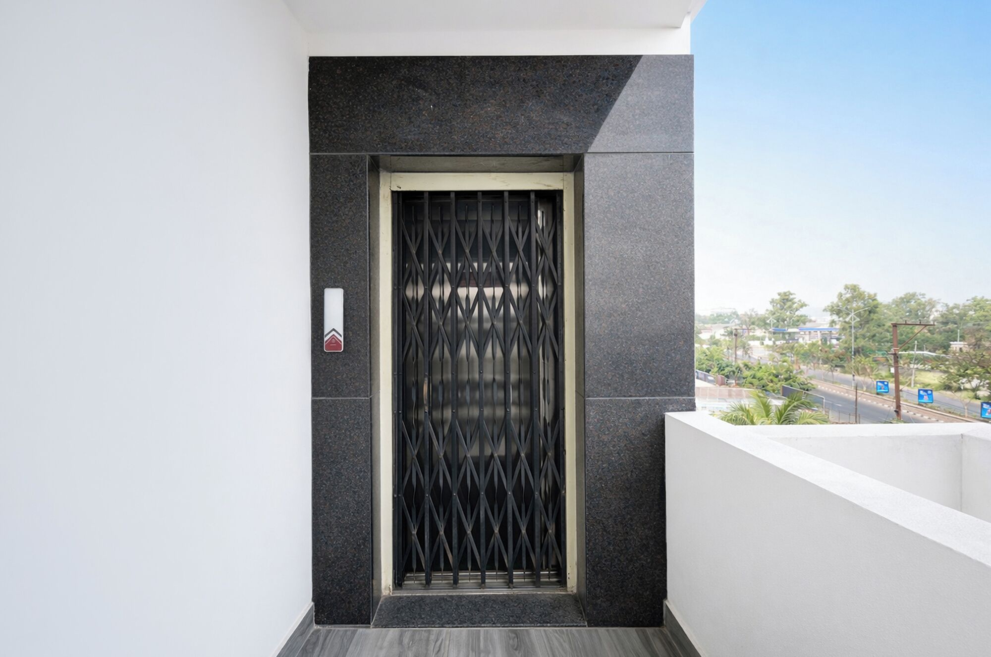Entrada de um edifício moderno com uma parede texturizada escura, um portão de metal e uma pequena placa.