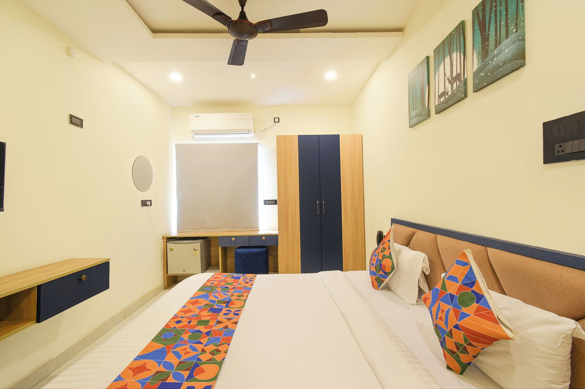 A bedroom with a bed, a desk, a wardrobe, and a ceiling fan.