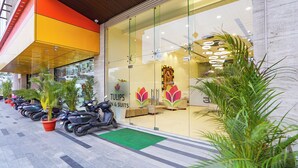 A storefront with a glass facade, a logo, and a green mat at the entrance. - Oriva Tulips Inn and Suites - Nr. Majestic (Bengaluru)