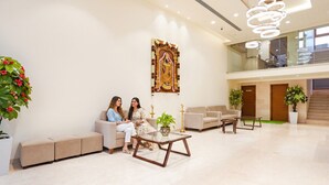 A spacious lobby with a high ceiling, a large decorative wall piece, and seating areas. - Oriva Tulips Inn and Suites - Nr. Majestic (Bengaluru)