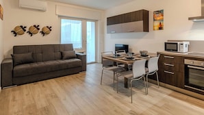A modern kitchen with a dining area, a sofa, and a TV. - Nice apartment for 4 guests with A/C, WIFI, TV and patio (Riva Del Garda)