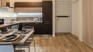 A modern kitchen with dark wood cabinets, a stainless steel range hood, and a dining area with a table set for two. - Nice apartment for 4 guests with A/C, WIFI, TV and patio (Riva Del Garda)