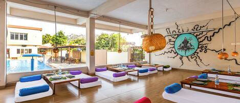 A spacious indoor area with seating arrangements, a dining table, and a view of an outdoor swimming pool.
