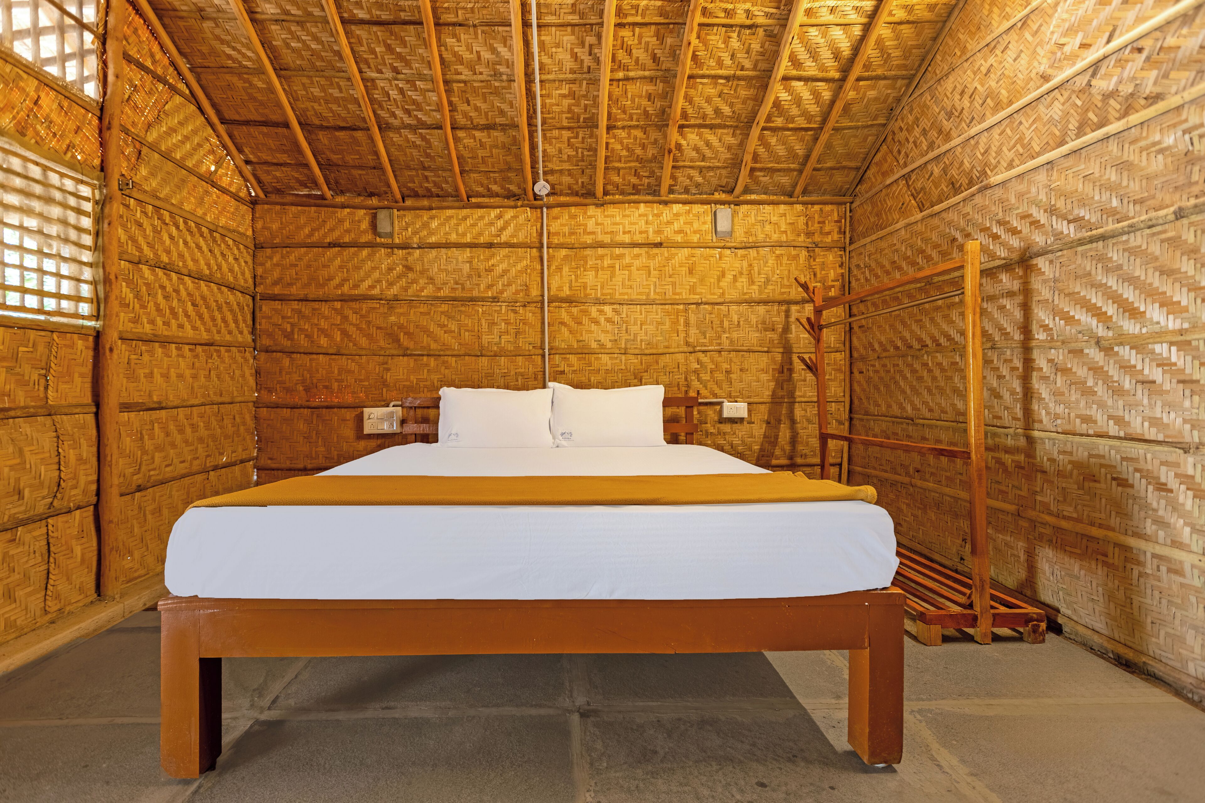 Una habitación con una cama grande, paredes de madera y techo de paja.