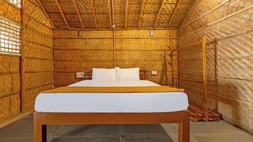 Una habitación con una cama grande, paredes de madera y techo de paja.