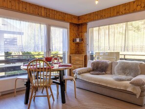 A cozy room with wooden walls, a sofa, a dining table with chairs, and large windows. - Ramuges 37A by Interhome (Veysonnaz)