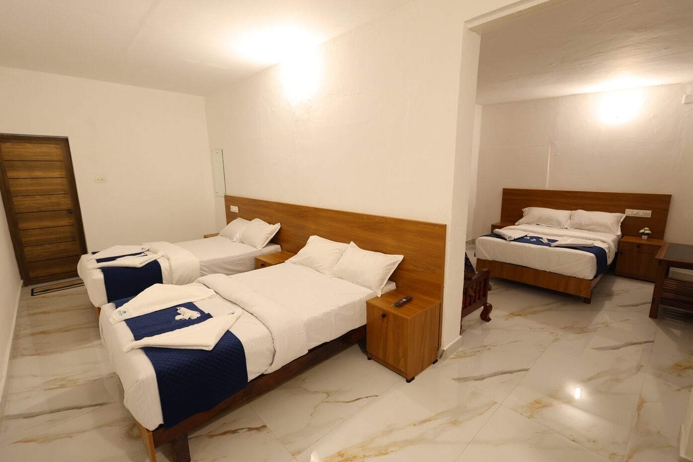 Een hotelkamer met twee enkele bedden, een houten hoofdeinde, een nachtkastje en een klein tafeltje.