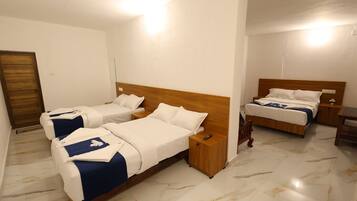 Een hotelkamer met twee enkele bedden, een houten hoofdeinde, een nachtkastje en een klein tafeltje.