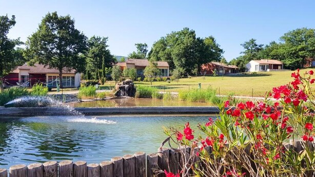 A residential area with houses, a pond with a waterfall, and a wooden fence. - Villa in Pyrenees With Stunning Views (Quillan)