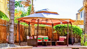 A covered outdoor seating area with a pool, wooden fence, and a pergola. - Luxurious 5 Bedroom Retreat with Saltwater Pool (Elk Grove)