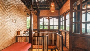 Ein Zimmer mit gewebter Wand, einer Holzbank, einer Treppe und großen Fenstern.