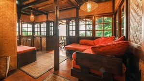 Ein rustikaler Holzinnenraum mit Sofa, Gewebetapete und großen Fenstern.