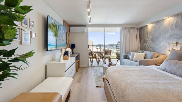 Un dormitorio moderno con una cama grande, un escritorio y un balcón con vistas.