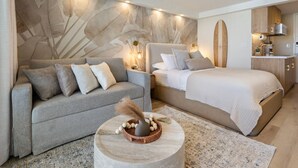 Un dormitorio moderno con sofá, cama y una mesita redonda con adornos.