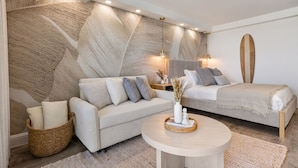 Une chambre moderne avec un grand lit, un canapé, une table basse ronde et un mur décoratif.