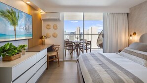 A modern hotel room with a bed, a desk, and a balcony with a city view. - Oceanview Luxe Retreat – Modern Coastal Elegance (Honolulu)