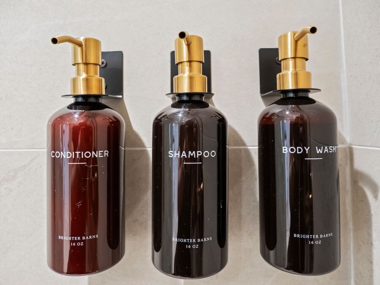 Trois flacons de produits de la marque Brightner Barns : un après-shampoing, un shampoing et un gel douche, chacun doté d’un distributeur à pompe.