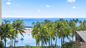 A resort with a pool, palm trees, and a beach view. - Waikiki Ocean Wave Escape: Coastal Luxe (Honolulu)