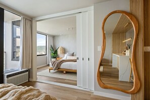 A modern bedroom with a large bed, a walk-in closet, and a large mirror. - Waikiki Luxury Ocean Escape 33F – 1 Parking (Honolulu)