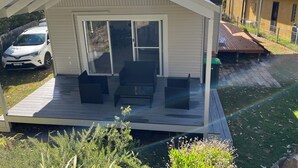 Een klein, gelijkvloers huis met een overdekte veranda en schuiframen.